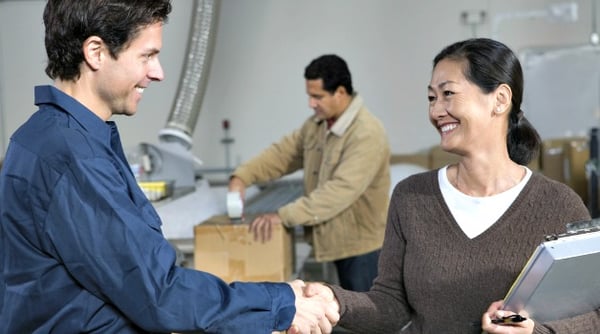 Man and woman shaking hands, another man working in the background