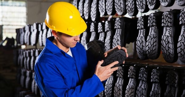 Man working in shoe sole factory, inspecting shoe sole