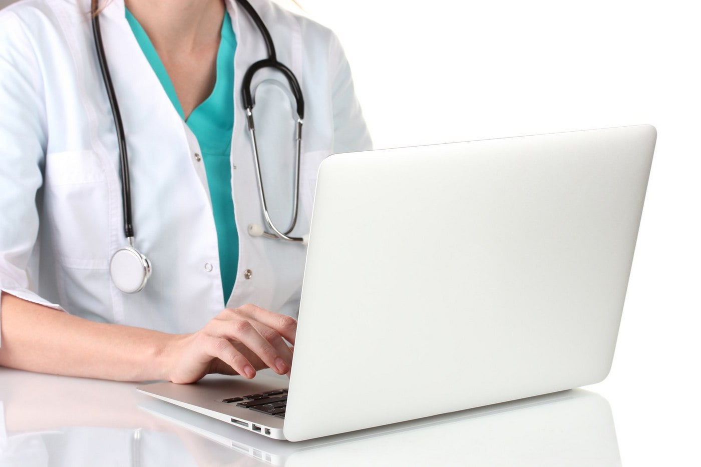 Healthcare professional with a stethoscope using a laptop on a white reflective surface.