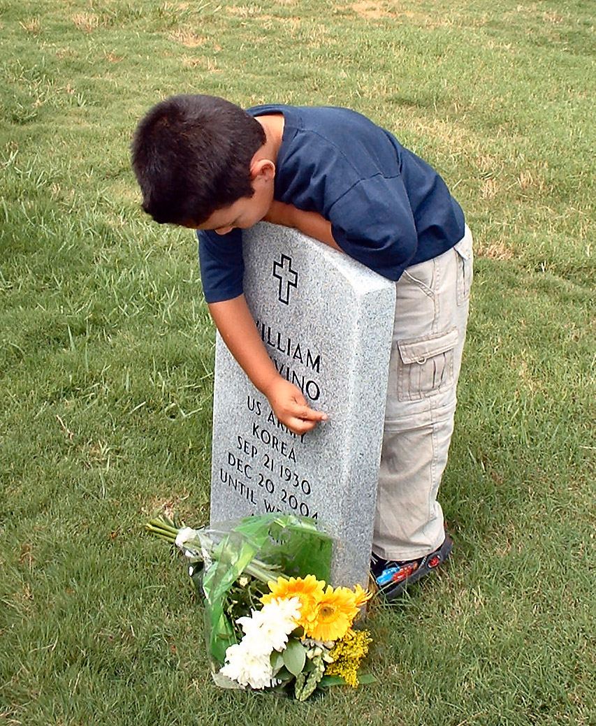 boy-embracing-grave-with-fresh-flowers autistic-boy-embracing-grave-with-fresh-flowers