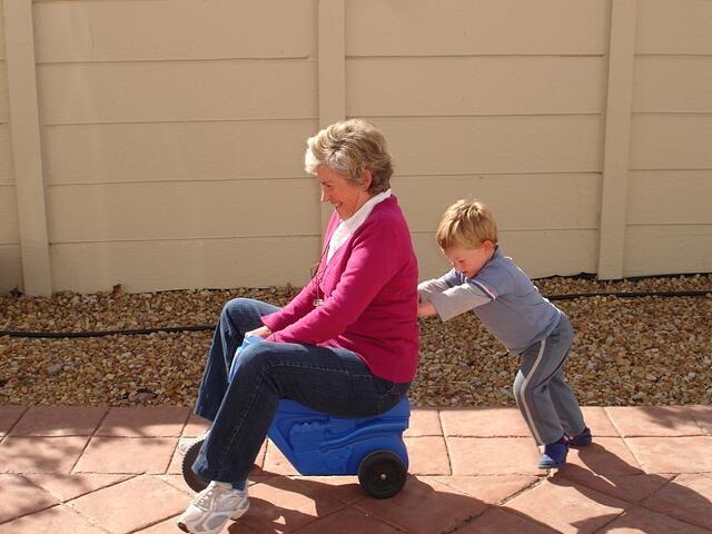 Child_pushing_grandmother_on_plastic_tricycle-157511-edited