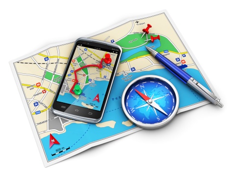 a smartphone with a maps app overlaid on top of a map with a compass and pen