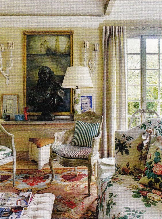 A beige and red Aubusson rug provides a dramatic contrast to the floral chintz fabrics as in the English hunting lodge of designer Nicky Haslam.