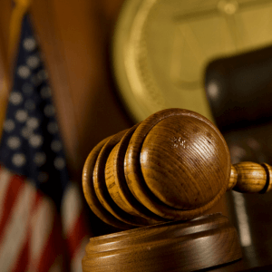 Picture of a gavel in a courtroom with an American flag in the background