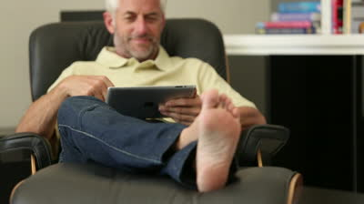 stock footage man relaxing with his tablet sitting in recliner chair in living room resized 600