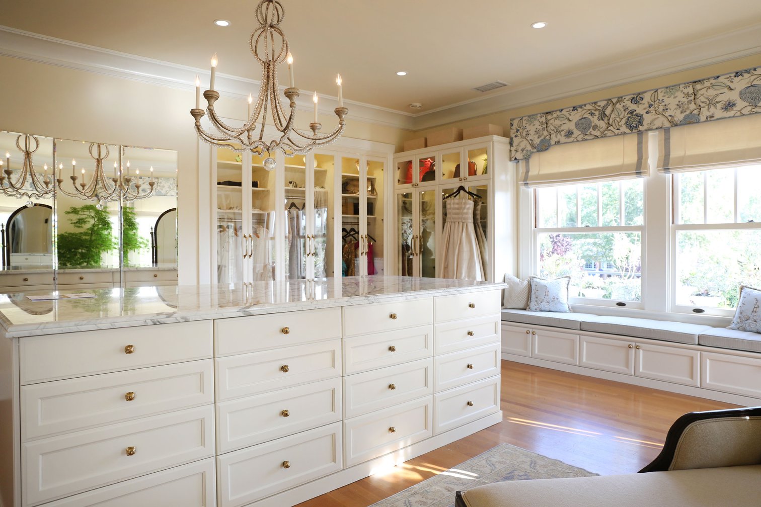 This California home’s walk-in wardrobe and dressing room is appointed with custom-designed built-ins including several closets, a center island, and banquette; chandeliers and huge windows provide ample light. This California home’s walk-in wardrobe and dressing room is appointed with custom-designed built-ins including several closets, a center island, and banquette; chandeliers and huge windows provide ample light.