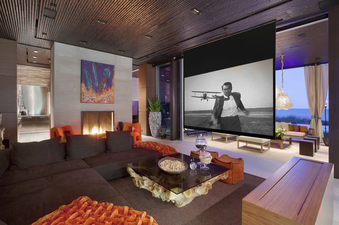 This media room at an oceanfront retreat in Vero Beach, Florida, features a fireplace; drop-down, large-format screen; and full wet bar with backlit onyx surround. This media room at an oceanfront retreat in Vero Beach, Florida, features a fireplace; drop-down, large-format screen; and full wet bar with backlit onyx surround.