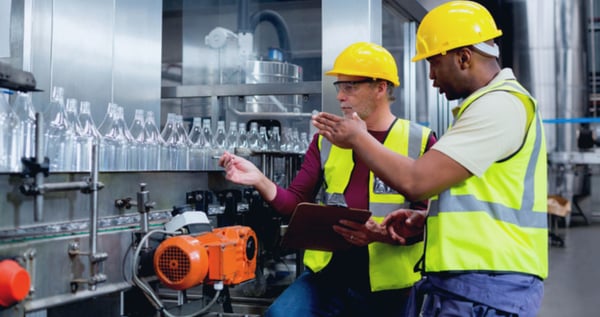 Factory workers discussing next to a production line