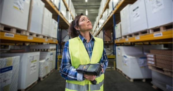 Women working in warehouse, looking up at shelves
