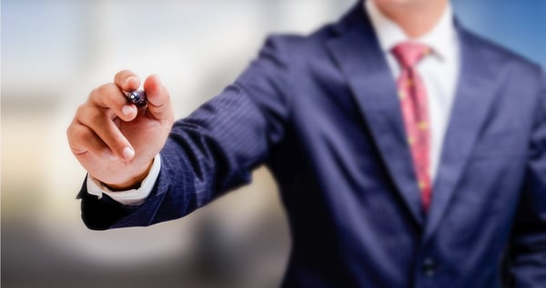 Man in suit holding a pen up