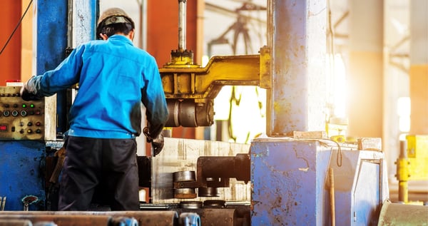 factory machinery shown on the foreground whilst a factory worker is working on the background