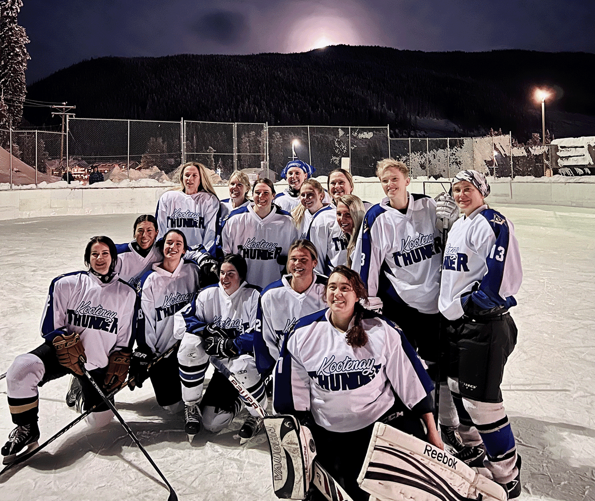 Group of women's hockey players on an outdoor rink.