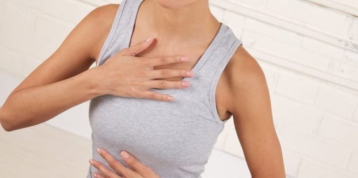 a woman holding her chest because of dysfunctional breathing
