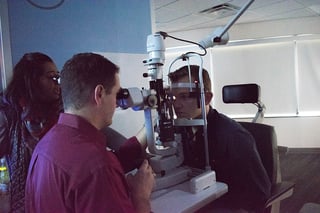The author, Matt Marzullo, Vice President of Global Sales takes his turn at the slit lamp on PCO student Tyler Ellsworth with direction from Dr. Bhawan Minhas. 