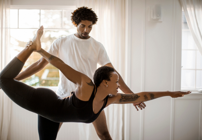 Woman practicing yoga with male yoga instructor.