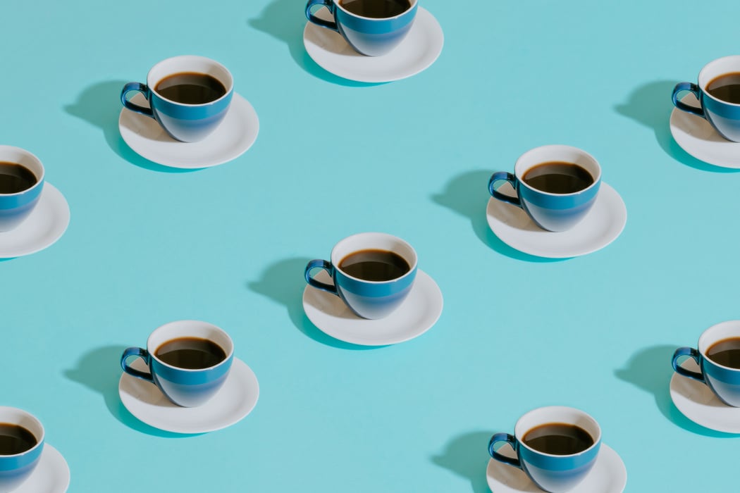 A pattern of coffee cups on top of a teal background.