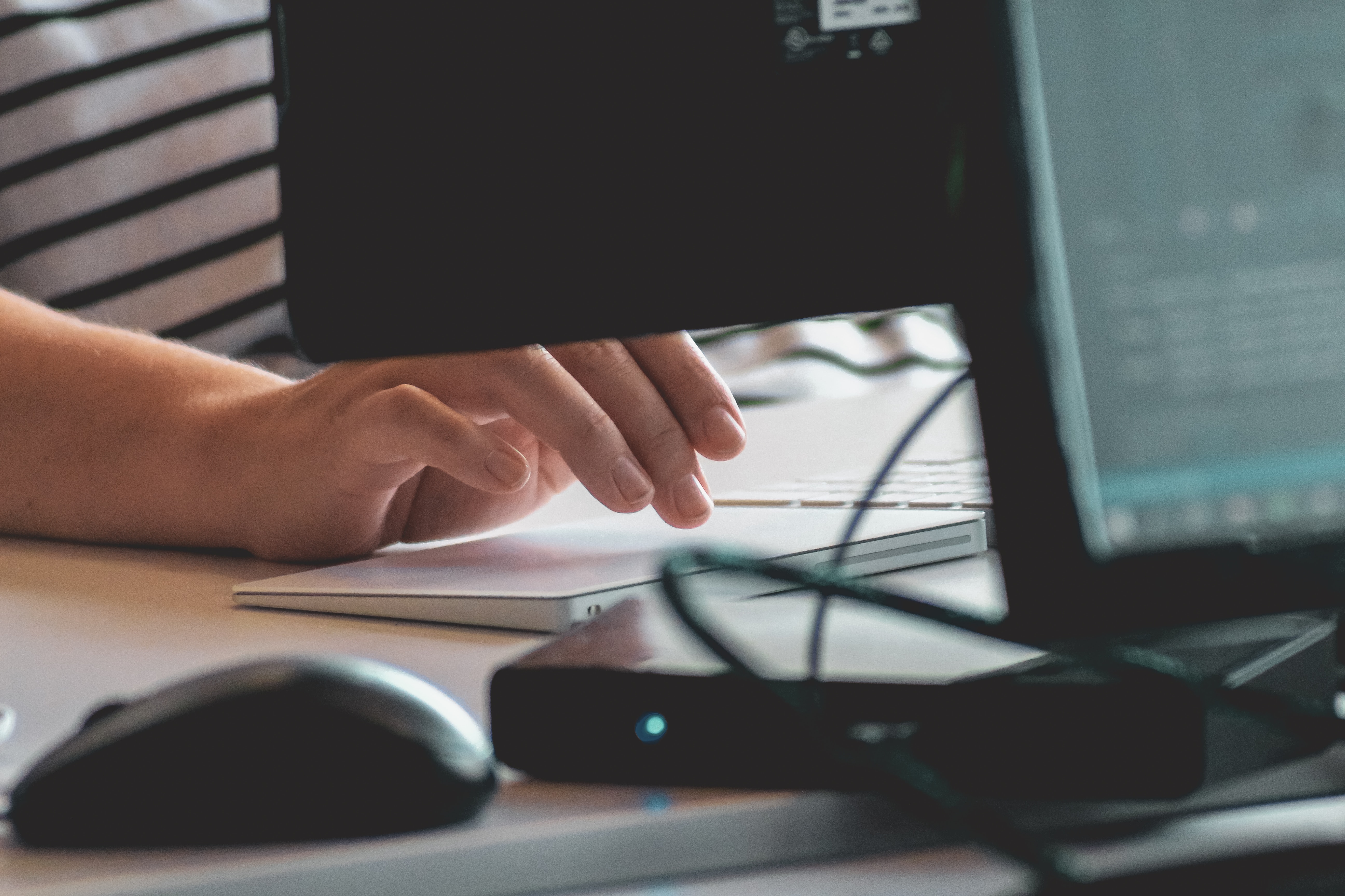 A hand typing at a desktop computer.
