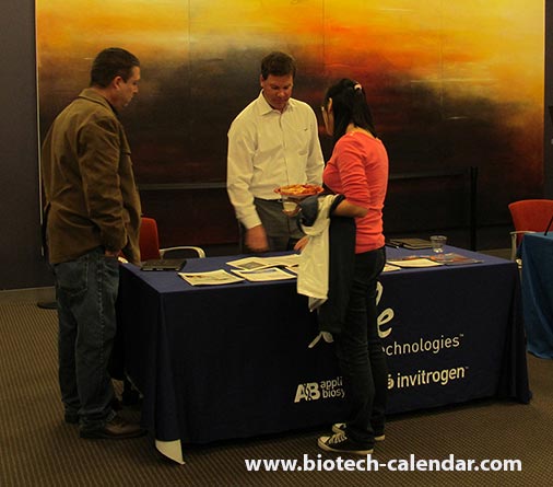 A vendor talks to a couple scientists about his company's bioresearch technology.