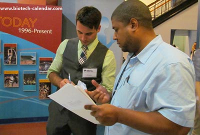 A well dressed exhibitor offering information to a scientist at the BioResearch Product Faire™ event, held at Armory Track & Field.