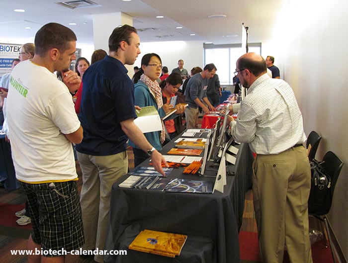 A vendor explains his company's research technology to a group of attendees.