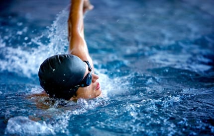 Professional male swimmer in a pool with hat and goggles