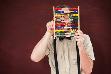 Geeky hipster holding an abacus against desk