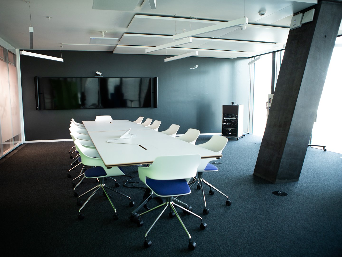 Grosses Sitzungszimmer mit Stühlen, Tisch und zwei Displays