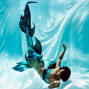 Finfolk Productions Instagram account showing woman underwater wearing mermaid fin