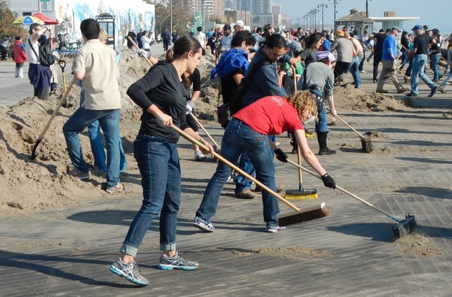 Crowd of volunteers cleans up a boardwalk after a hurricane
