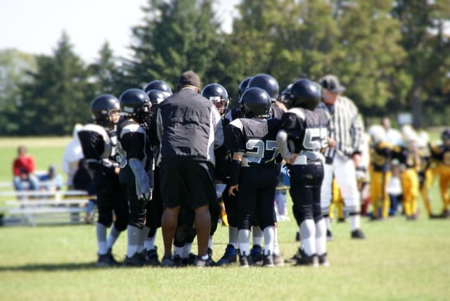 Youth huddle on a football field