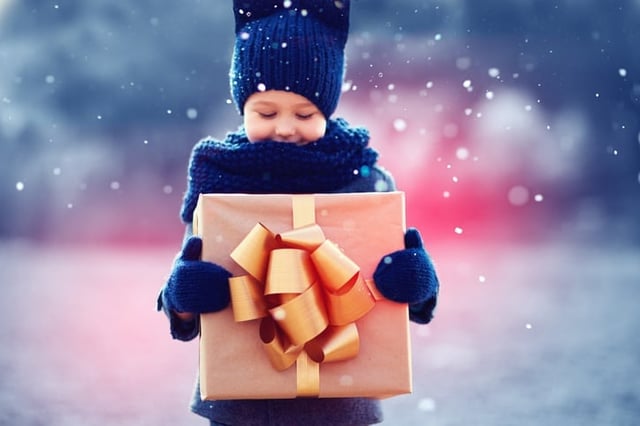 Child in winter weather gear holding a present