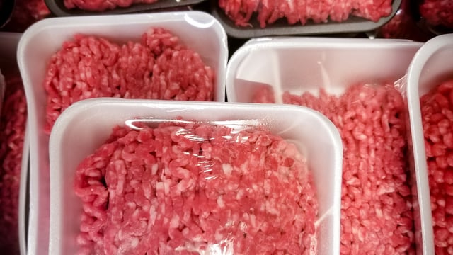 Packs of raw ground beef stacked up on top of each other. 