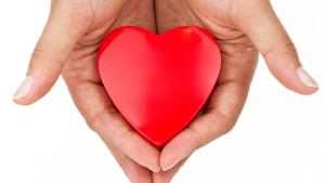 A heart shape is held in the palms of two hands.