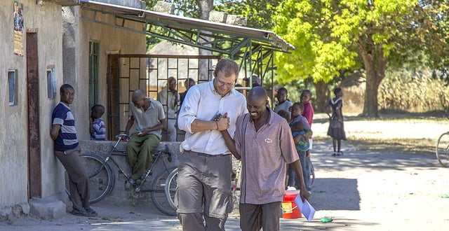 A volunteer joining hands with a local coordinator in the middle of the town.