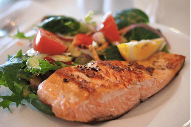 Grilled salmon and salad are served on a white plate.