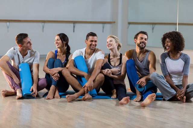 Group of people sitting on floor in fitness studio