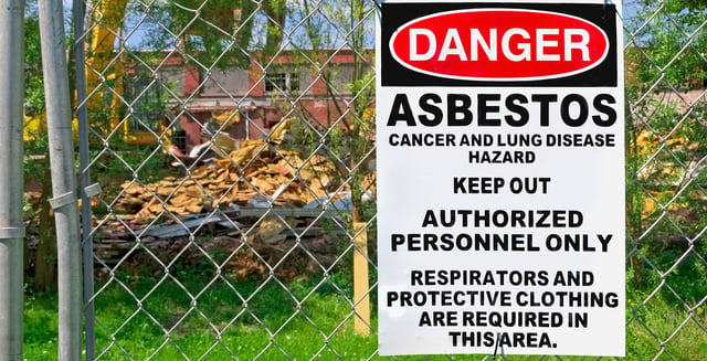 asbestos warning sign on fence in front of construction