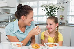 Mother and daughter eat breakfast. Link takes you to Kidsheath's page on breakfast.