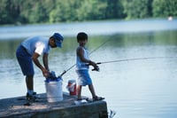 A boy fishes with his father. Link goes to Fish and Wildlife Services page on Special Events.