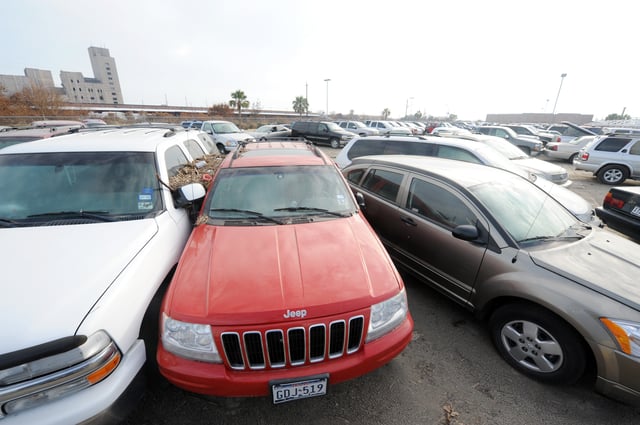 Several flood-damaged cars are crowded together in a parking lot.