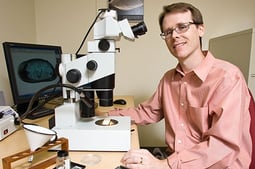 Paleontologist Gene Hunt poses in front on his microscope. Link takes you to Smithsonian's Science How page. 