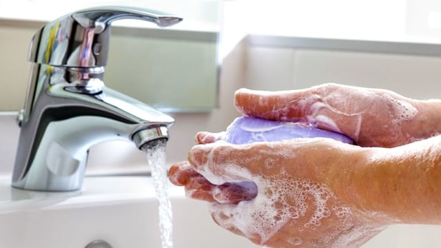 Washing hands with soap in a running sink
