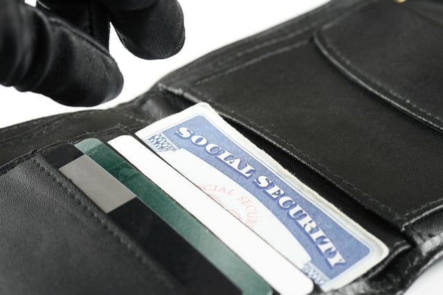 A gloved thief reaches for a Social Security card in a stolen wallet