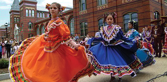 Young women in bright, traditional Mexican dresses dance on the National Mall. Young women in bright, traditional Mexican dresses dance on the National Mall.