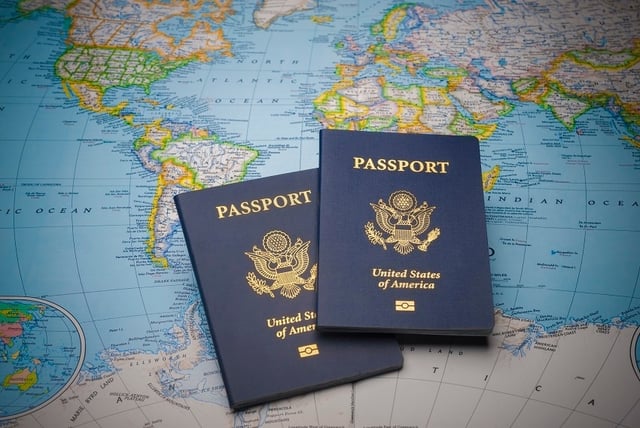 Two U.S. passports laid upon each other on top of a world map