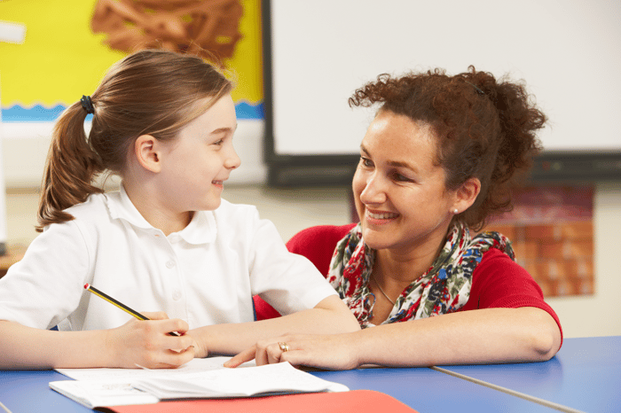 schoolgirl studying in classroom with teacher