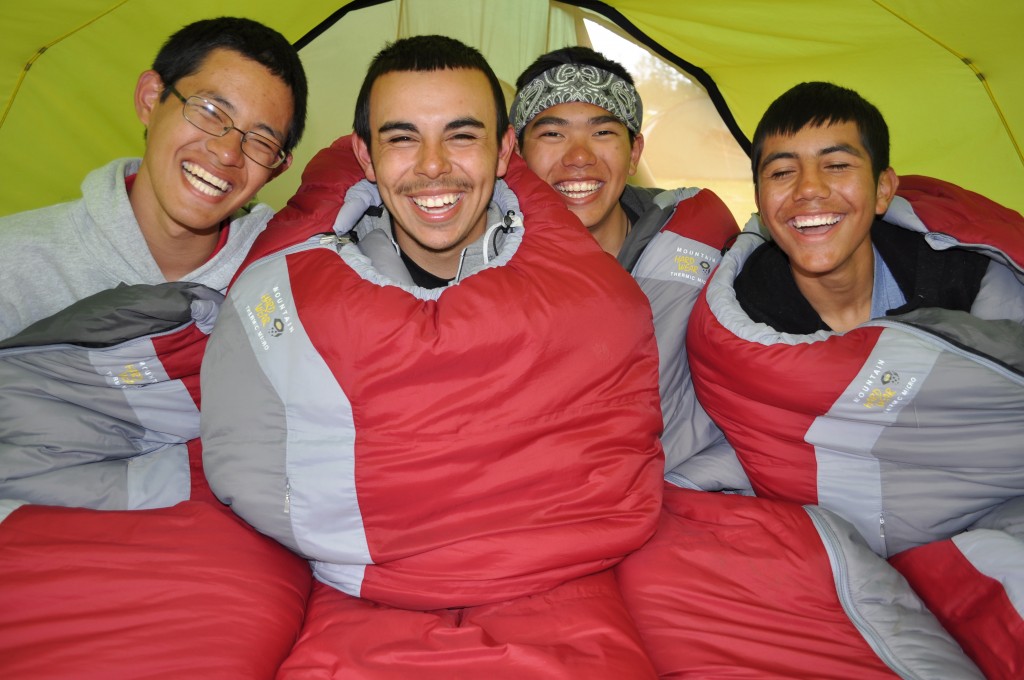 Four smiling teens in sleeping bags