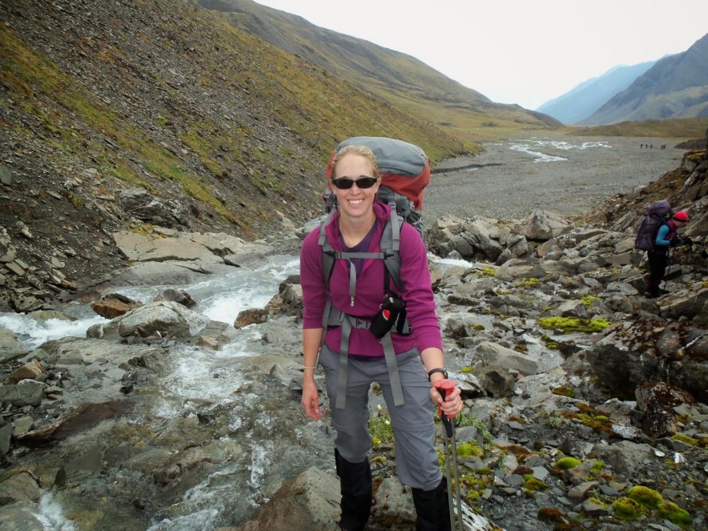 Smiling backpacker standing beside a rocky stream