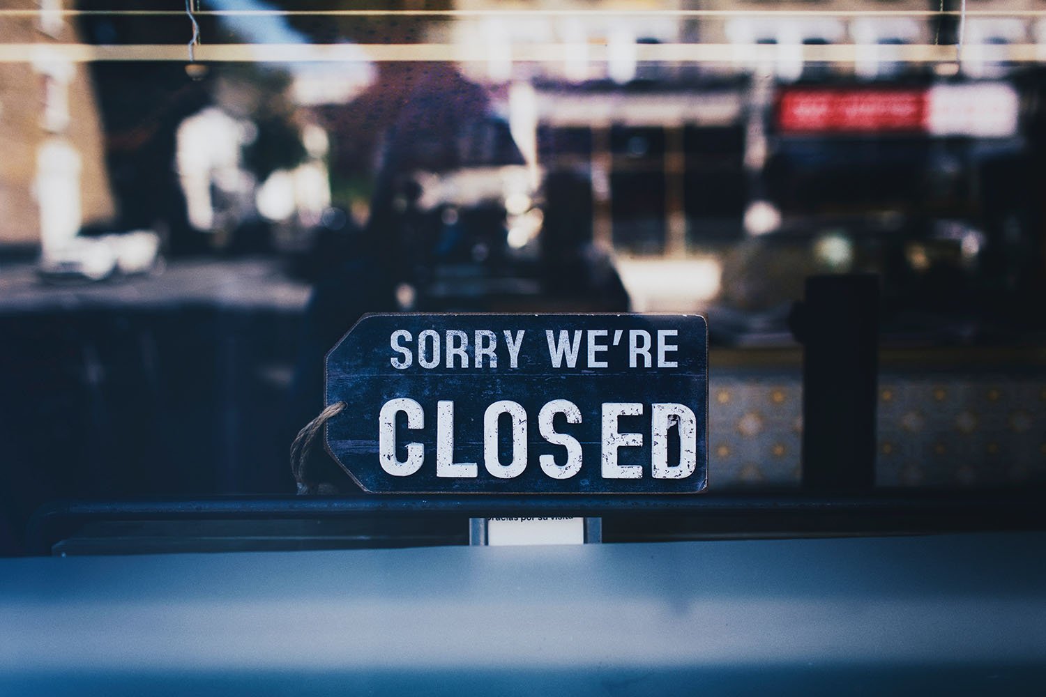 "Sorry we're closed" sign hanging in glass window