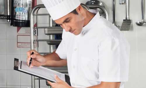Chef filling out a checklist on a clipboard